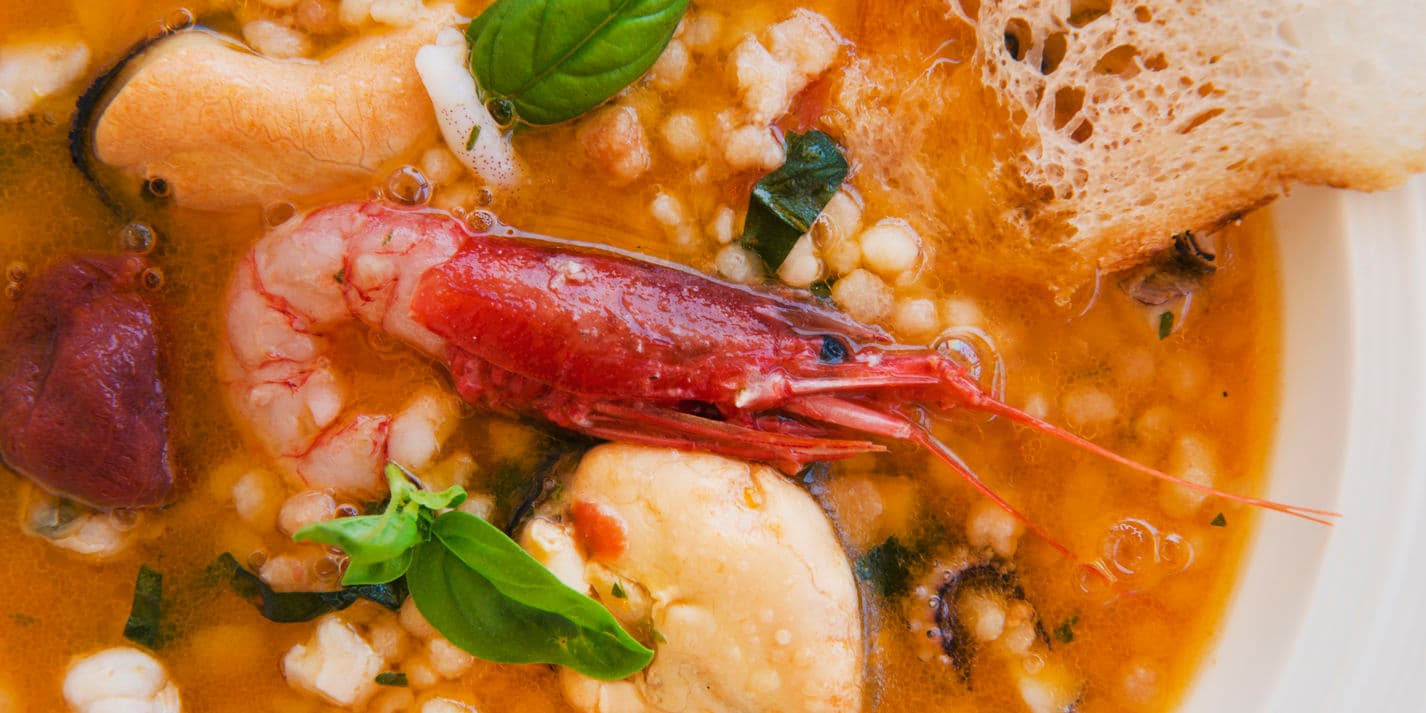 Seafood soup with fregula, basil and citrus